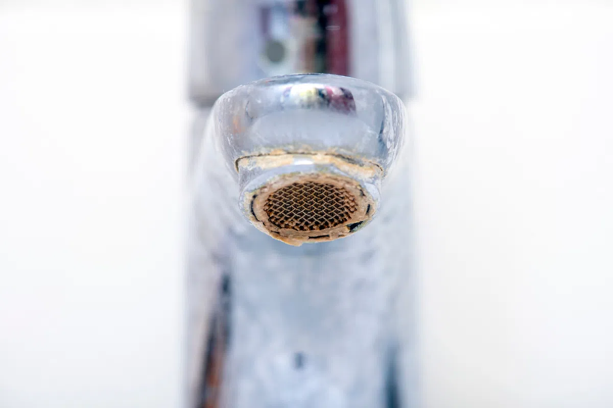 A close up of a rust kitchen faucet showing signs of corrosion
