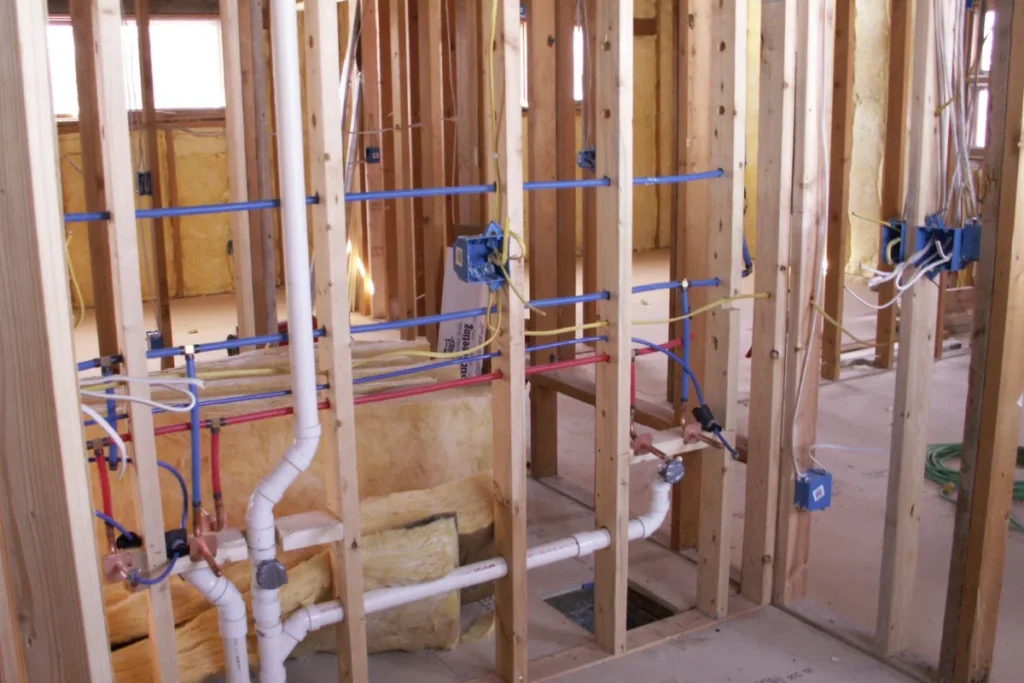Rough-in plumbing with PEX water lines and PVC drain pipes installed inside framed residential walls during new construction.