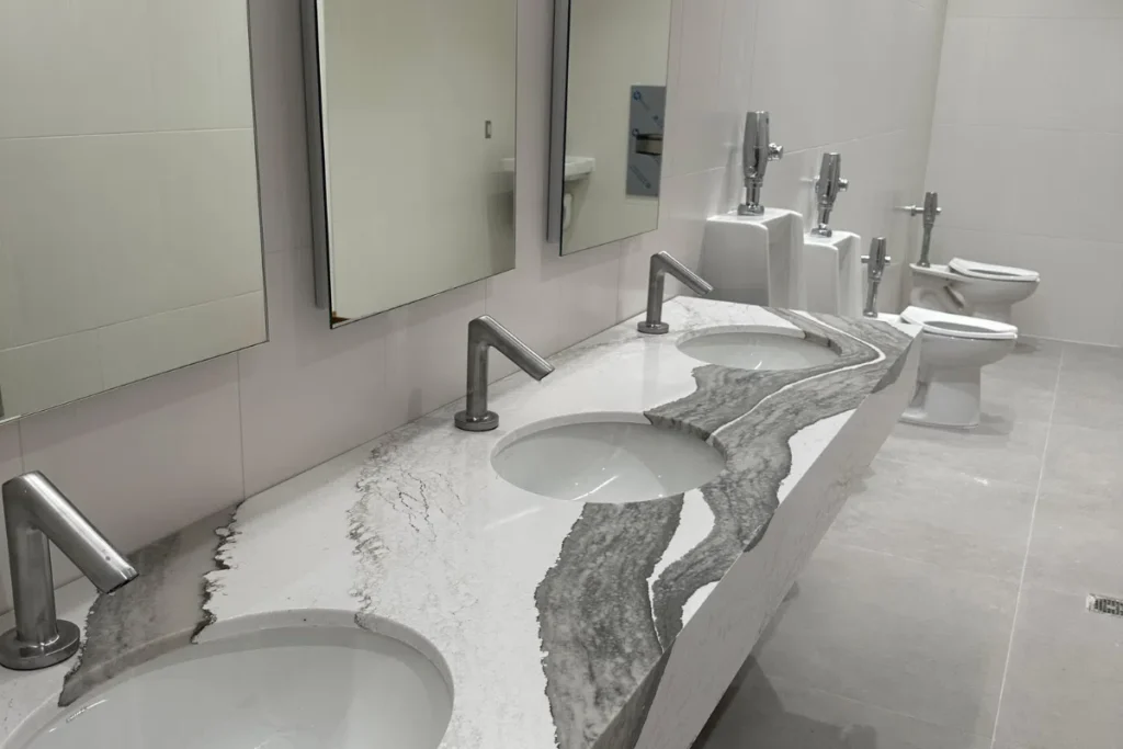 Modern commercial restroom with multiple sinks, marble countertop, and updated plumbing fixtures.