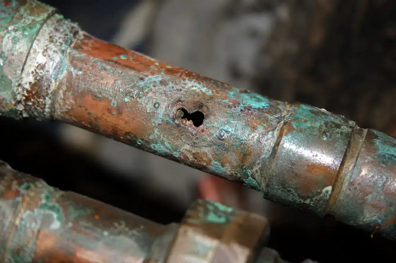 Corroded copper water pipe with pinhole leak, showing severe pipe deterioration that may require whole-home repiping services.